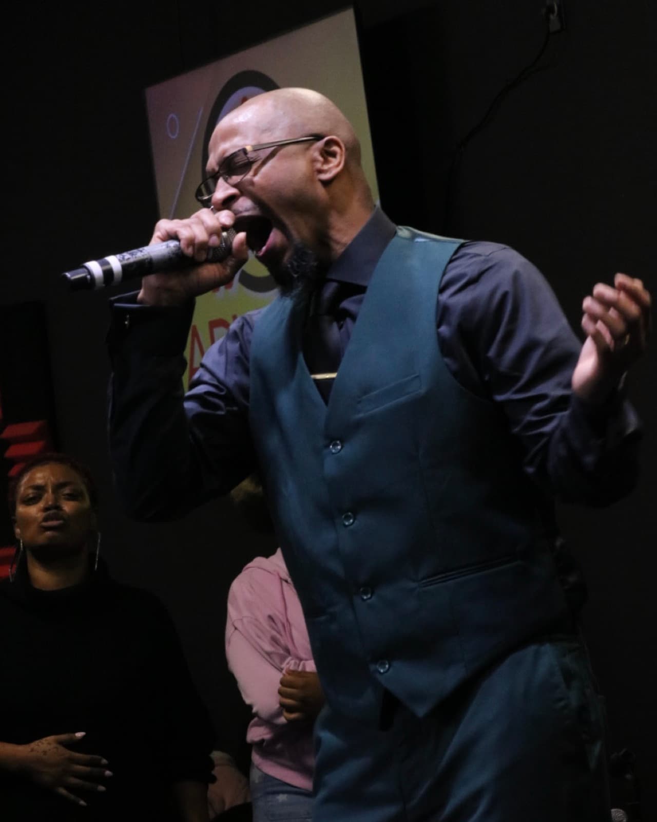 A worship leader singing into a microphone during a service at Advance Church